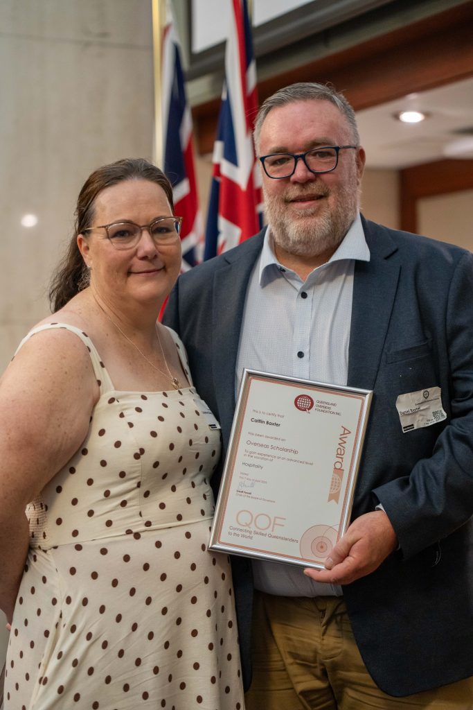 Image of Caitlin Baxter and partner, smiling with her certificate