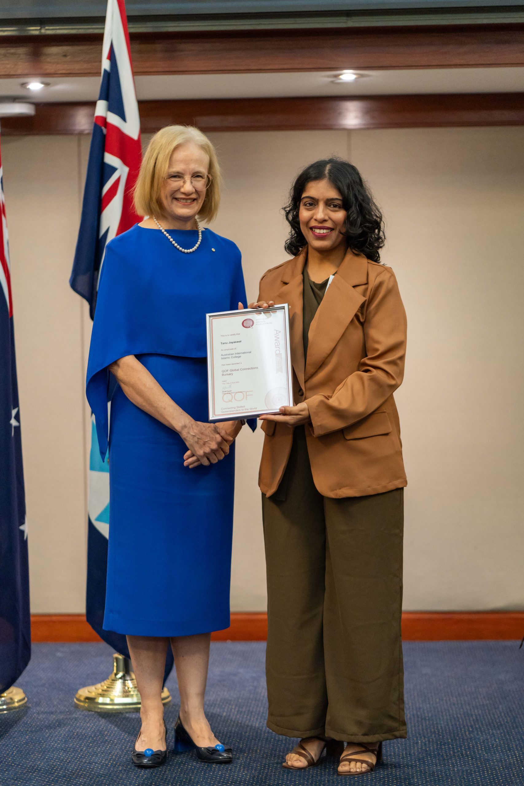 The governor of Queensland with Tanu Jayaswal smiling with her certificate