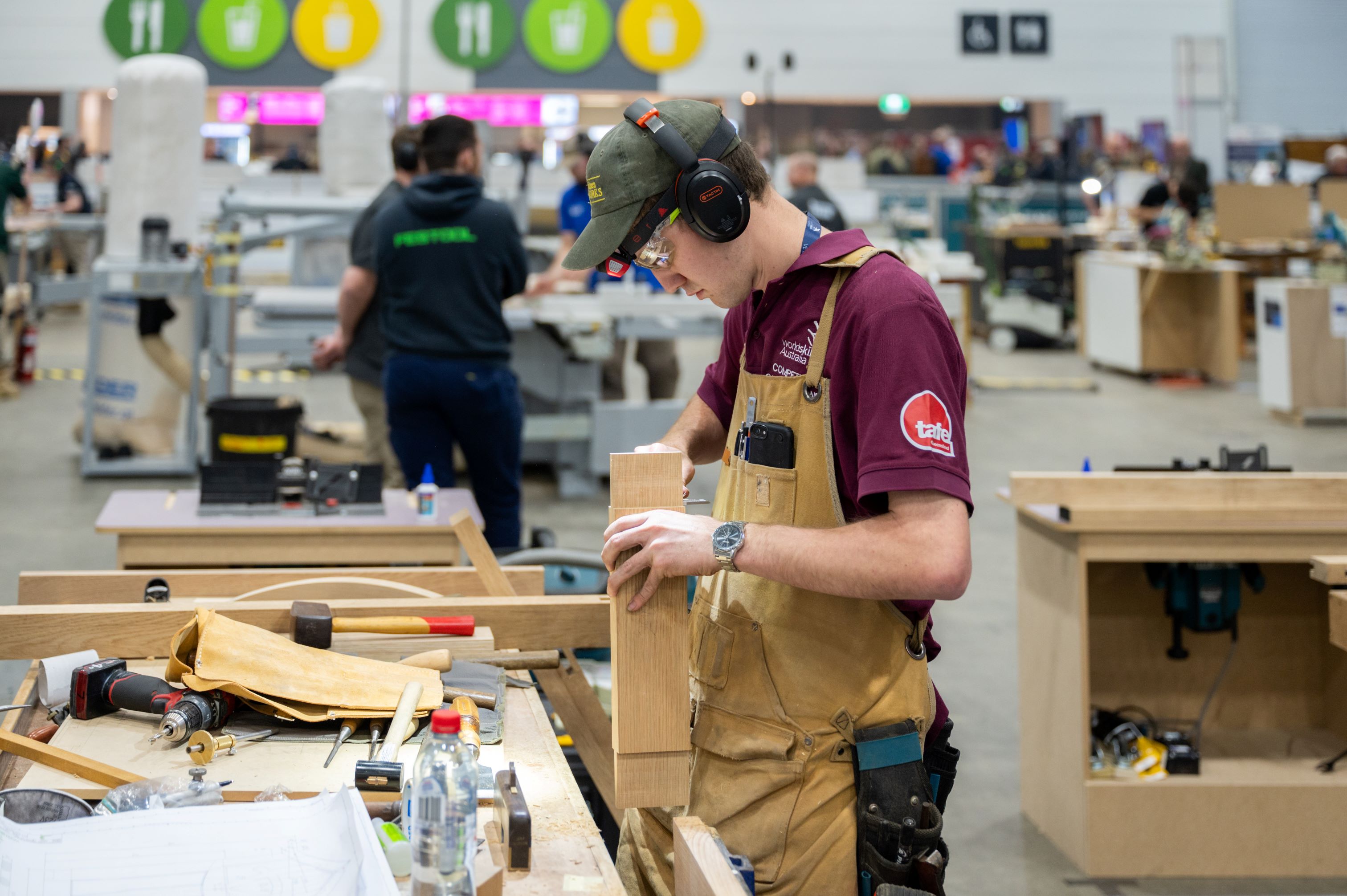 Image of a Queensland carpenter wearing his maroon TAFE shirt, working on joinery