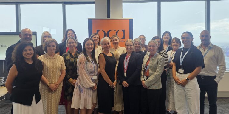 Group of people in business attire standing in front of a large window and DCA banner.