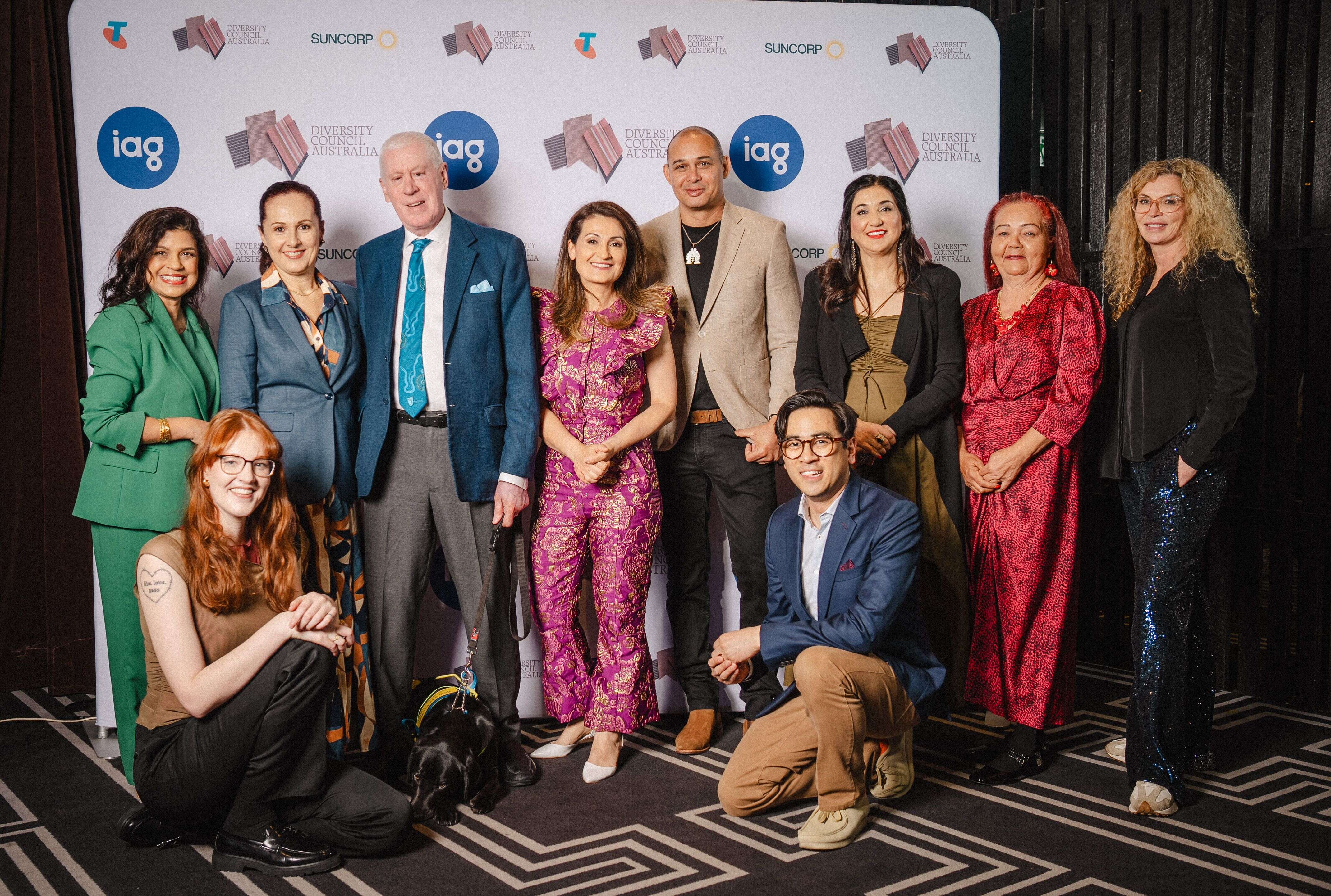 Speakers and DCA representatives smiling and posing in front of media banner at the 2024 Diversity Debate