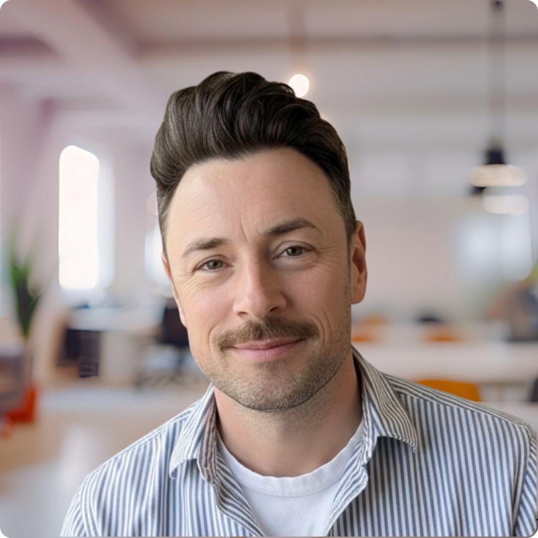 Headshot of Rob Larisch-Morgan, a young white man with short brown hair and moustache, wearing a white t-shirt and striped button down shirt.