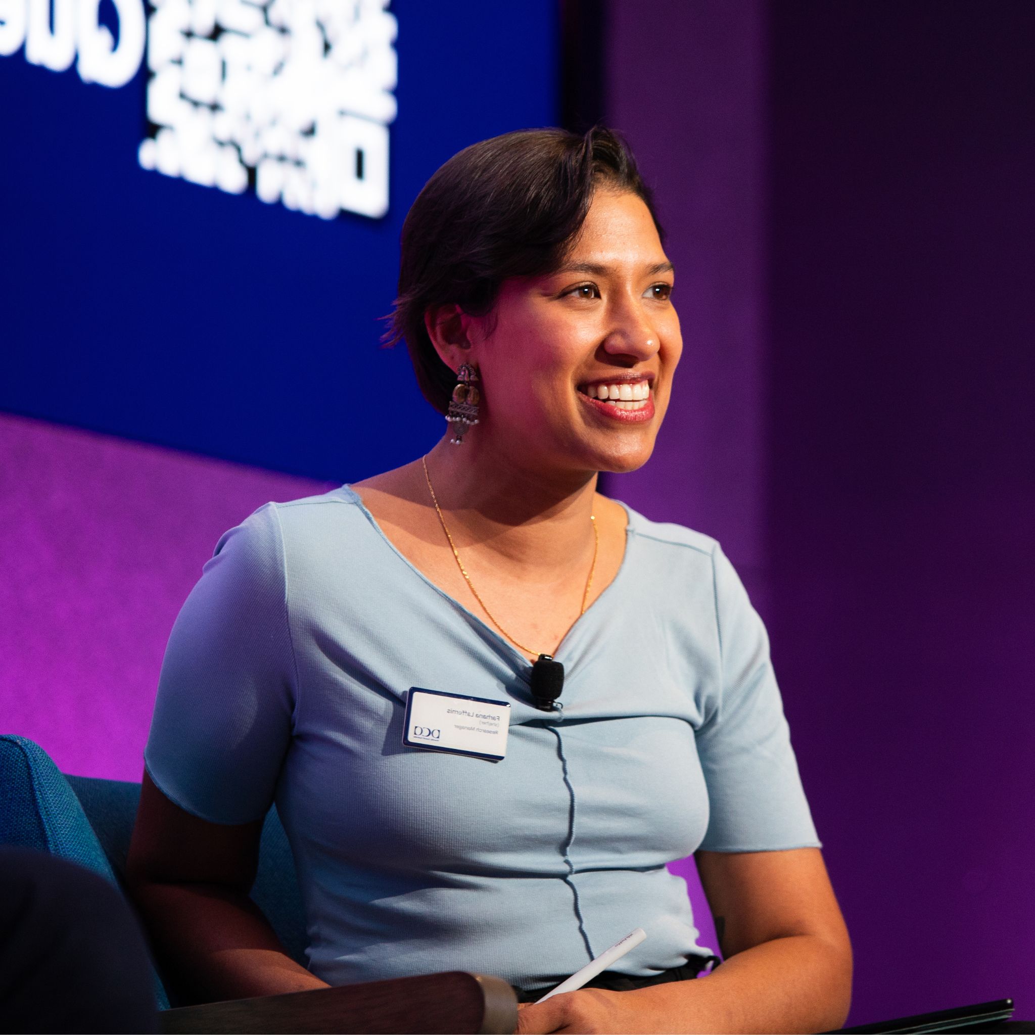 Farhana Laffernis in a blue shirt smiling on a panel at a DCA event