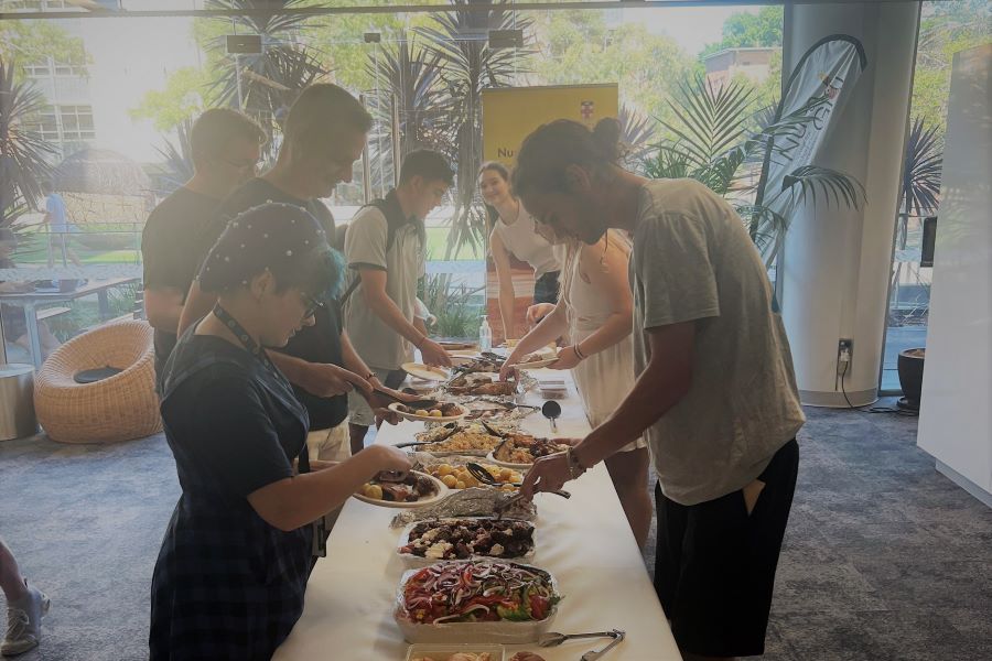 Photo of a group of students serving food from a lunch table